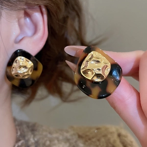 Detail of 18k gold plated earring with leopard acetate pattern and hammered metal texture
