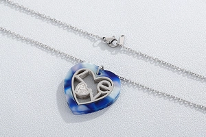 Macro detail of heart pendant with blue marble texture and silver LOVE lettering