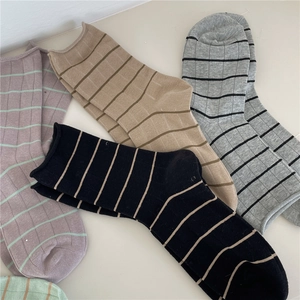 Detailed close-up of four ribbed crew socks in black, beige, gray, and light purple tones