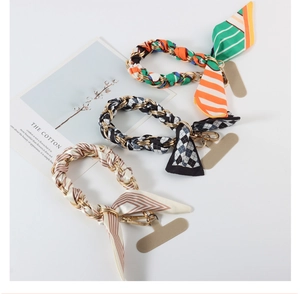 Three silk scarf wristlet phone straps with gold chains in geometric and plaid patterns