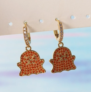 Close-up of gold ghost earrings with orange and clear zircon stones for Halloween