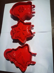 Close-up of red plastic Christmas baking set featuring snowman, snowflake, and tree shapes