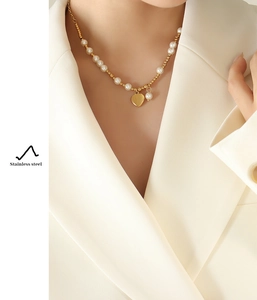Close-up of gold plated stainless steel heart pendant necklace with white pearls on model