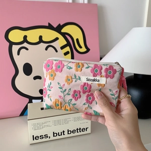 Close-up of pink floral fabric coin purse with white zipper and brand woven label