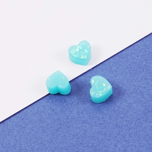 Detailed view of three teal heart-shaped resin charms with iridescent glitter on a dual-tone background