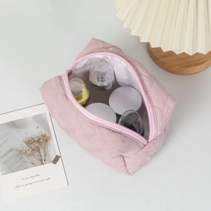 Inside view of pink quilted makeup bag showing large capacity for skincare bottles