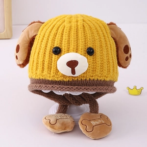 Detail of yellow knit baby winter hat with cute dog ears and embroidered bone charm