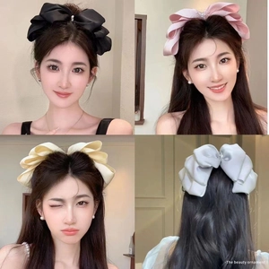 Detail showing oversized satin bow hair clips in black, pink, beige and grey colors