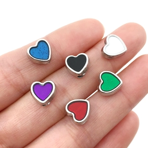 Macro shot of colorful heart-shaped alloy spacer beads displayed on a palm for DIY jewelry