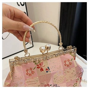 Detailed macro view of embroidered floral pattern and pearl clasp on the evening bag