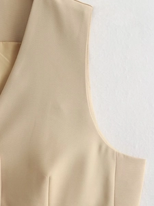 Détail macro de la texture sergé beige et des coutures sur la robe gilet femme