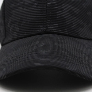 Macro detail of charcoal grey washed denim texture and fine stitching on baseball cap brim