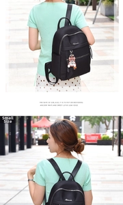 Black nylon mini backpack with bear charm shown on a model in an outdoor setting