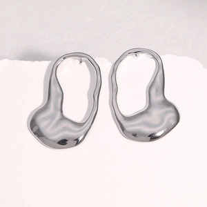 Macro shot of silver titanium steel earrings with irregular liquid-like metal design