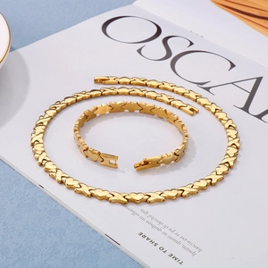 Detail of gold titanium heart and X link necklace and bracelet set on a magazine