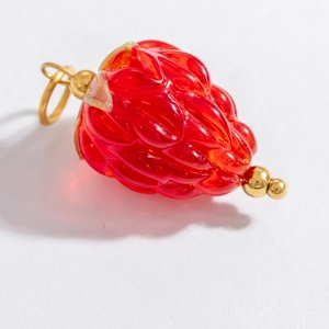 Macro shot of a red glass strawberry charm with an 18k gold-plated stainless steel clasp