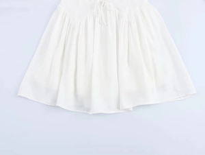 Detail of white ruffled mini dress hem with drawstring tie design and soft pleated texture