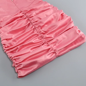 Détail de la robe courte en satin rose avec fronces texturées et fini brillant