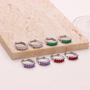Minimalist hoop earrings with baguette-cut zircons in four colors on stone background