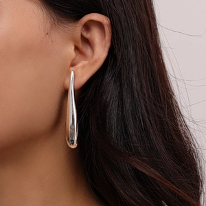 Macro detail of silver-finish teardrop drop earrings with high-polish mirror surface