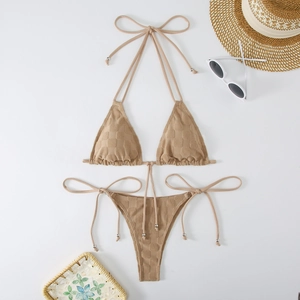 Flat lay of khaki checkered bikini with silver beads and summer vacation accessories