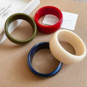 Macro view of geometric resin bangles in red, green, blue and beige marble finish