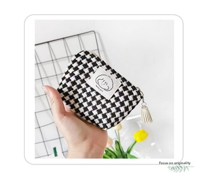 Detailed shot of knitted checkerboard mini pouch with happy girl label and tassel zipper