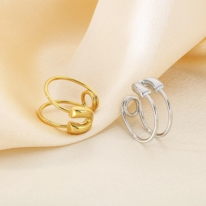 Close-up of gold and silver safety pin rings on elegant champagne silk background