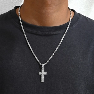 Gros plan d'un collier croix argenté serti de strass avec chaîne torsadée sur modèle