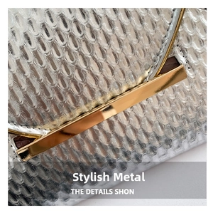 Detailed close-up of silver snakeskin texture with a gold metal clasp on a clutch bag
