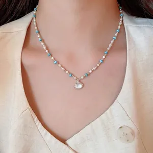 Elegante collana con perle azzurre e bianche e un pendente ovale in madreperla bianca