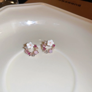 Dettaglio macro di orecchini a fiore traforati con petali di smalto e zirconi rosa