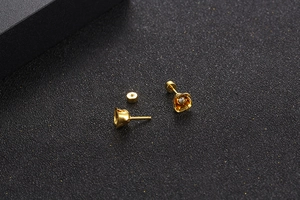 Macro shot of gold tulip earrings with white zircon accents and screw back design
