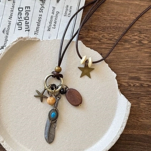 Close-up of bohemian pendant necklace with turquoise feather and starfish on stone tray