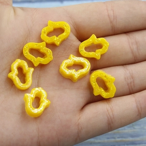 Seven yellow glitter resin Hamsa hand pendants held in palm showing size and texture