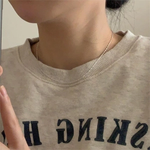 Selfie view of a minimalist thin silver water wave chain necklace worn by a woman