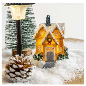 Close-up of a glowing wooden Christmas cabin with artificial snow and warm LED lighting