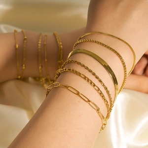 Close-up of stacked gold-plated stainless steel anklets including snake and paperclip chains