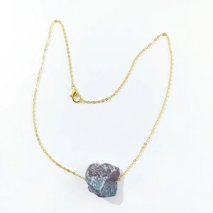 Detail of a natural purple fluorite crystal pendant on a gold chain necklace