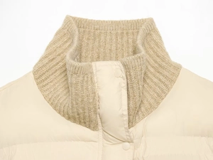 Detail of cream quilted jacket featuring a ribbed knit stand collar and snap buttons