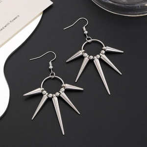 Macro detail of silver punk spike earrings with sharp metallic cones on textured dark background