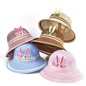 Detailed stack of kids straw sun hats featuring rabbit ears and embroidered text