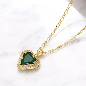 Gold heart necklace with green zircon pendant on white marble background