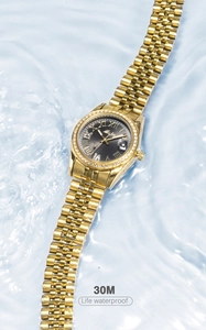 Detail of waterproof gold watch with black dial and crystals submerged in clear water