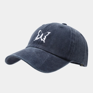 Detail shot of white butterfly embroidery on a washed dark gray cotton baseball cap