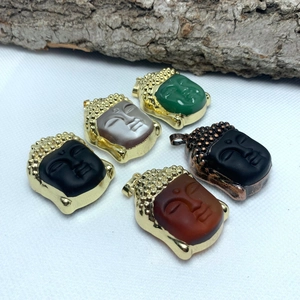 Macro detail of five multi-color Buddha head pendants with gold-plated metal edges