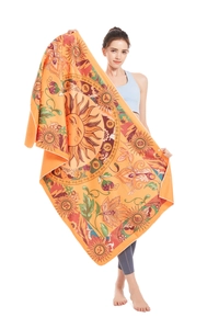 Detailed view of large orange beach towel with sun mandala pattern held by a model