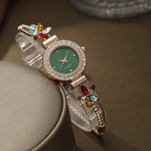 Macro detail of gold flower bracelet watch with green dial and sparkling crystal accents