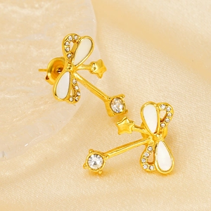 Detailed macro view of gold-plated dragonfly earrings with white enamel and zircon accents