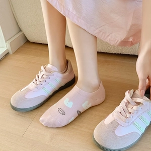 Pink low-top casual sneakers paired with cute cartoon rabbit ankle socks on wood floor